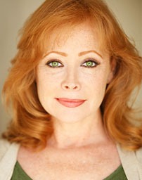 A woman with striking red hair and green eyes smiles warmly at the camera, conveying confidence and approachability.