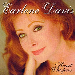 Earlene Davis's album cover for "Heart Whispers," featuring her portrait with striking green eyes and vibrant red hair, evokes emotions fitting for the music.